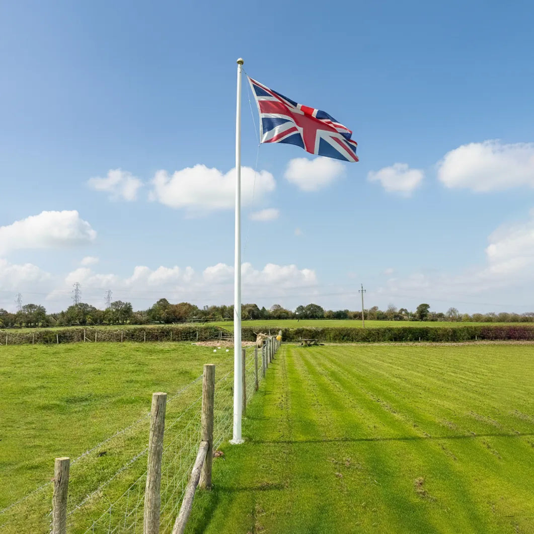 British flag on a flagpole in a green field with a clear blue sky