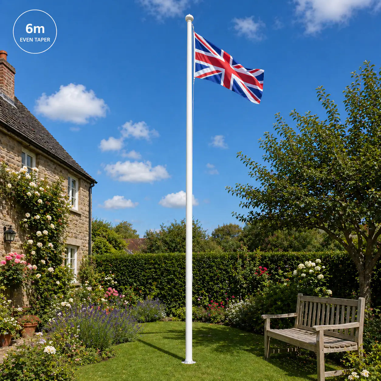 Flagpole with a British flag in a garden setting with a house and bench in the background.