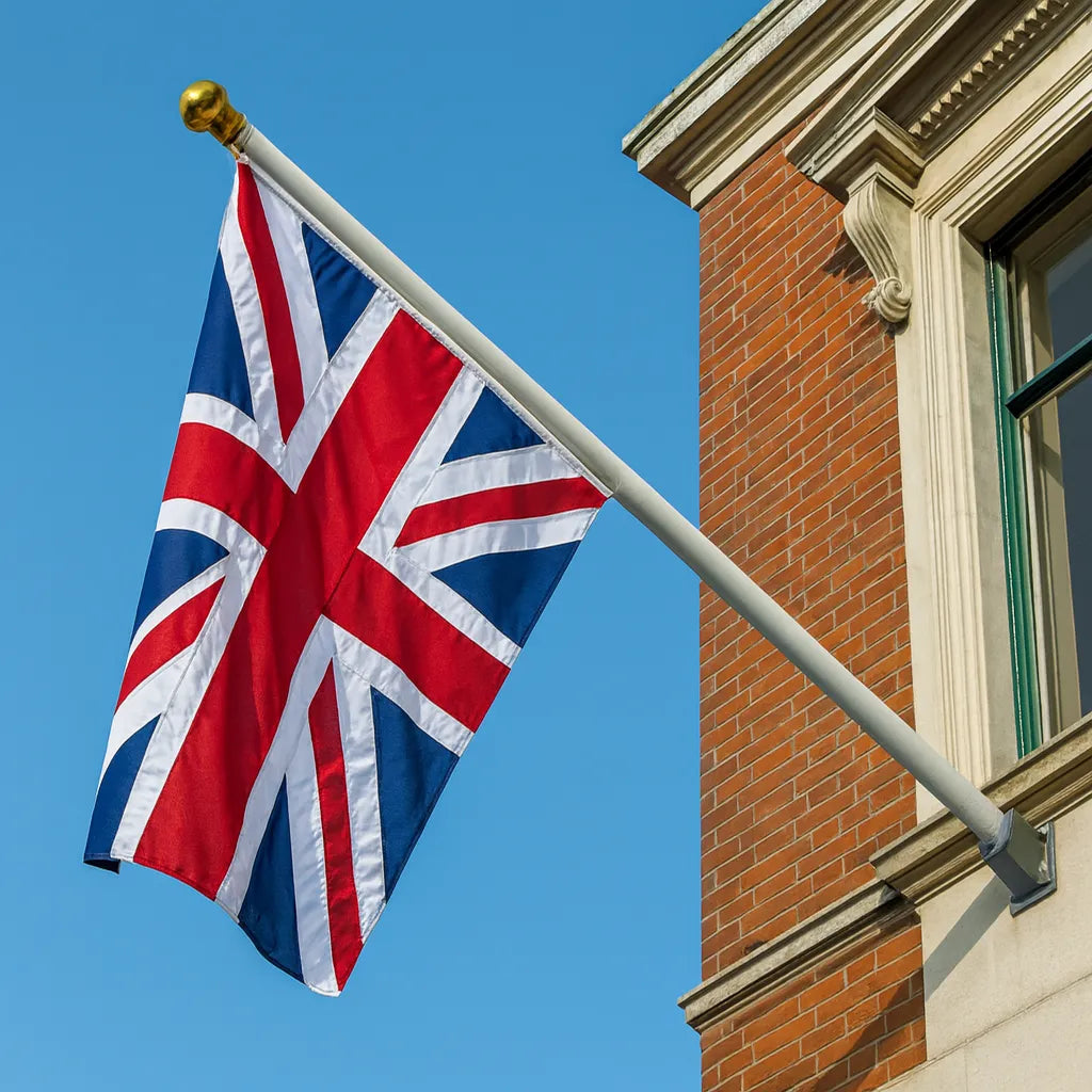 Union Jack flag on a pole against a blue sky with a brick building in the background